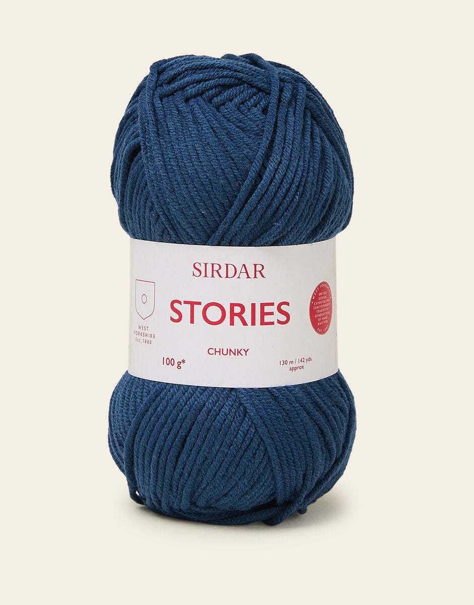 Blue skein of yarn with a Sirdar Stories label on a beige background